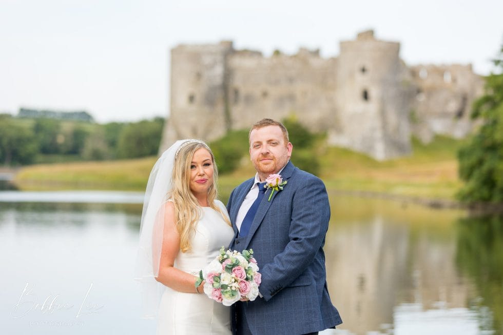 A bride and groom standing in front of a castle.