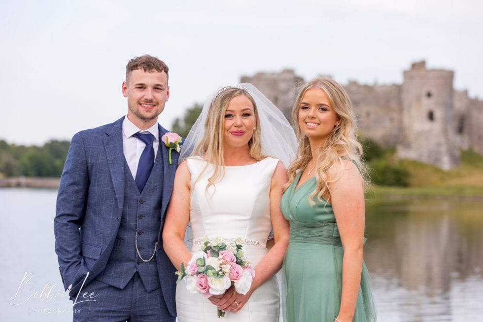Three brides and grooms posing in front of a castle.