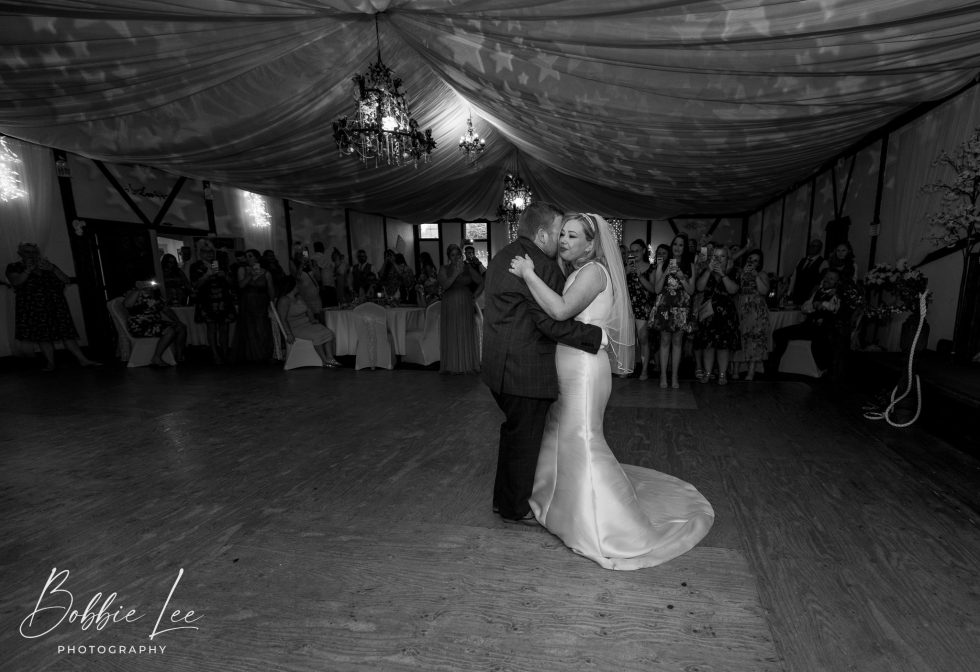 A bride and groom sharing their first dance in a large room.