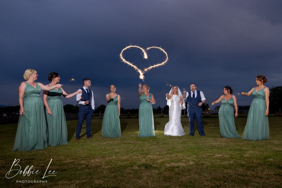 A group of bridesmaids holding sparklers in the air.