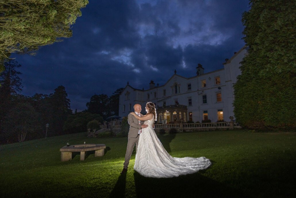 A south Wales bride and groom standing in front of a large mansion at night  captured by a wedding photographer.