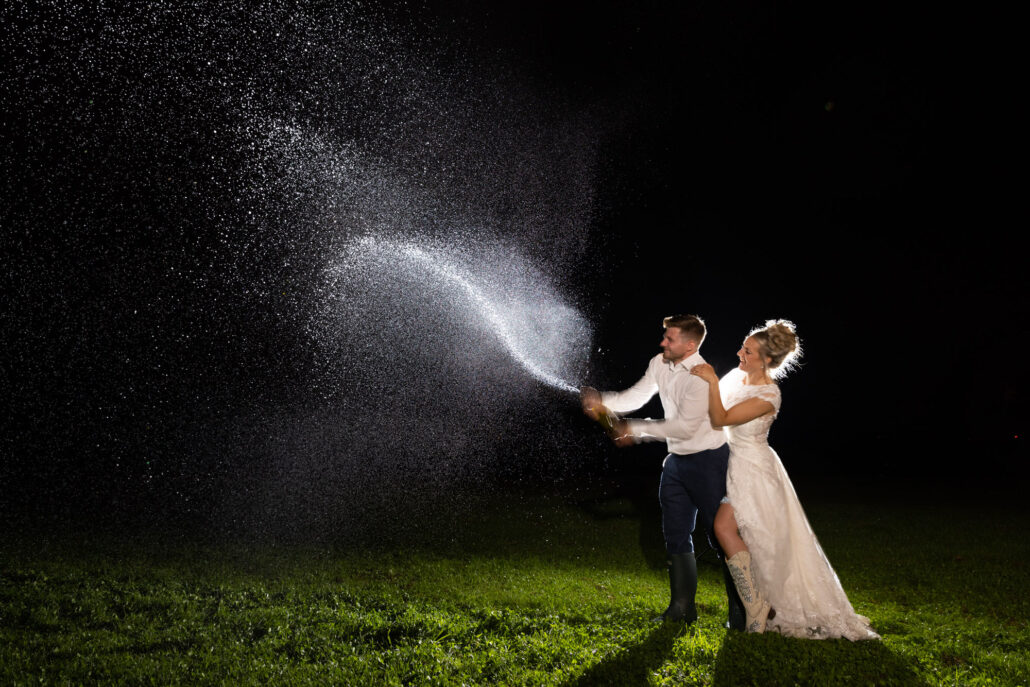 A south Wales wedding photographer captures a playful couple spraying water during their evening celebration.