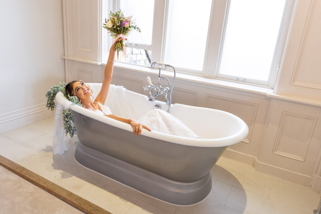 South Wales wedding photographer captures a bride gracefully immersed in a bathtub with flowers.