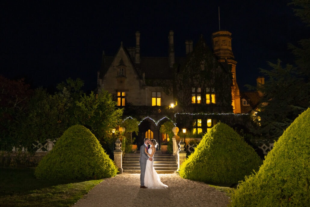 A South Wales wedding photographer captures a couple posing in front of a castle at night.