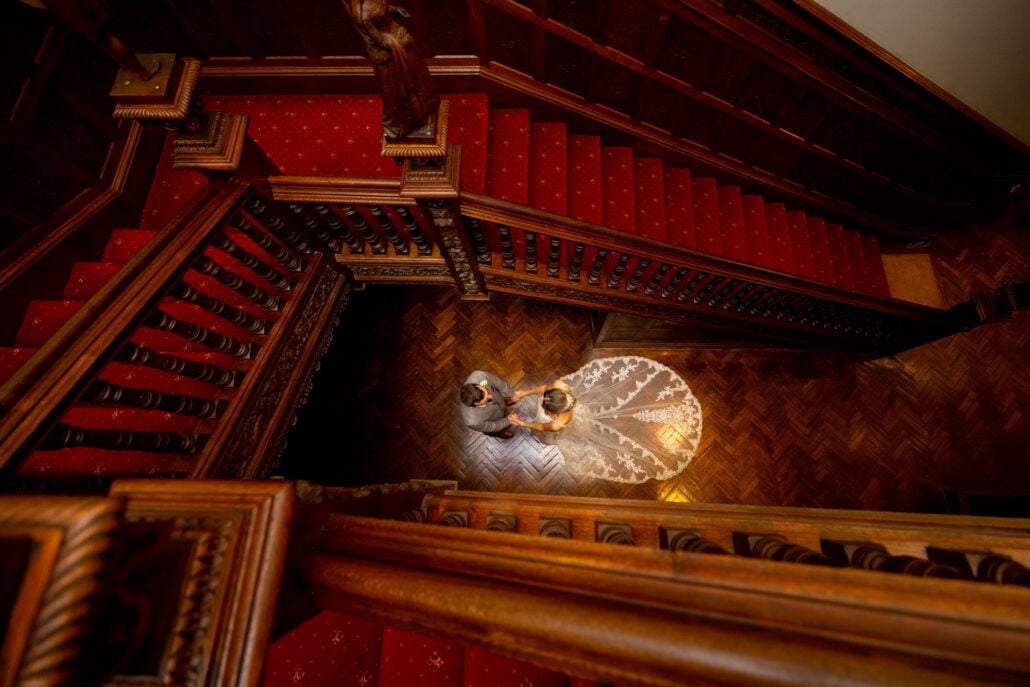 A South Wales wedding photographer capturing a bride and groom on the stairs of a mansion.