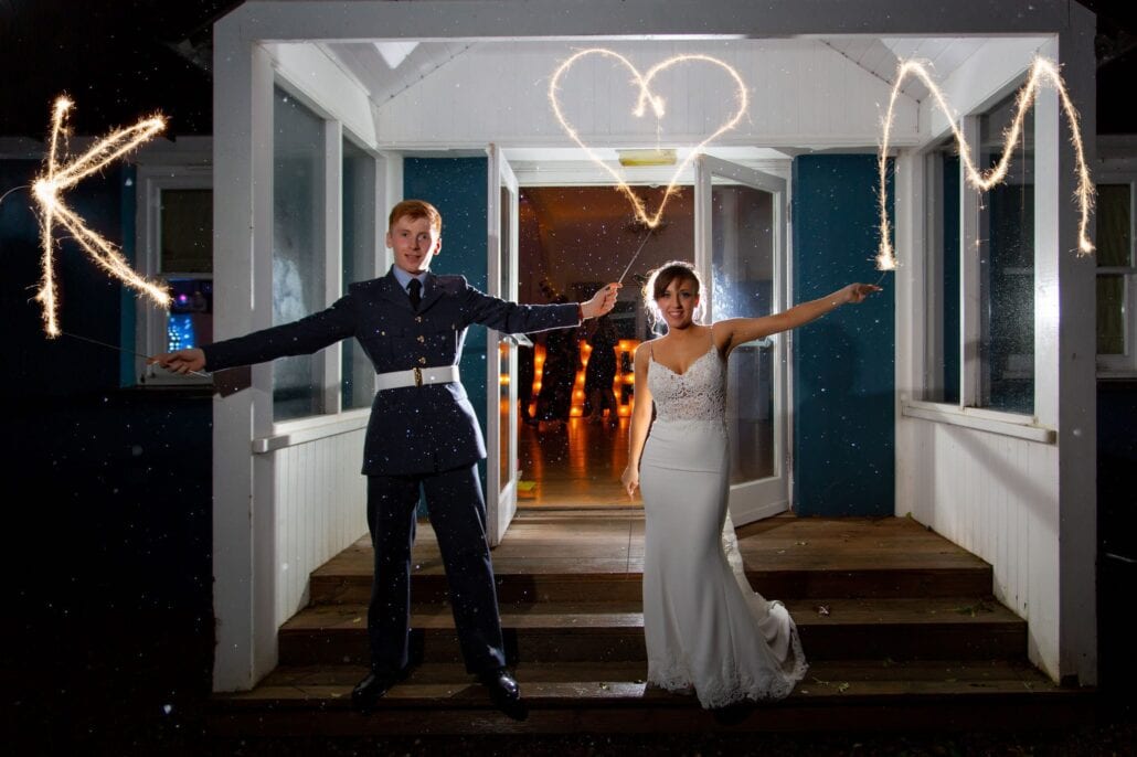 A south wales wedding photographer captures a bride and groom holding sparklers in front of a door.