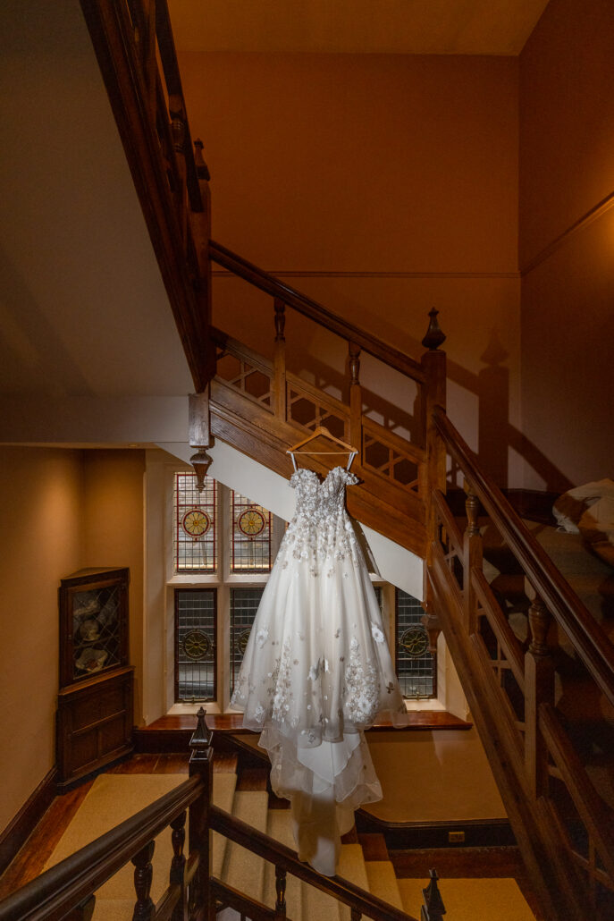 A wedding dress hanging on a staircase.