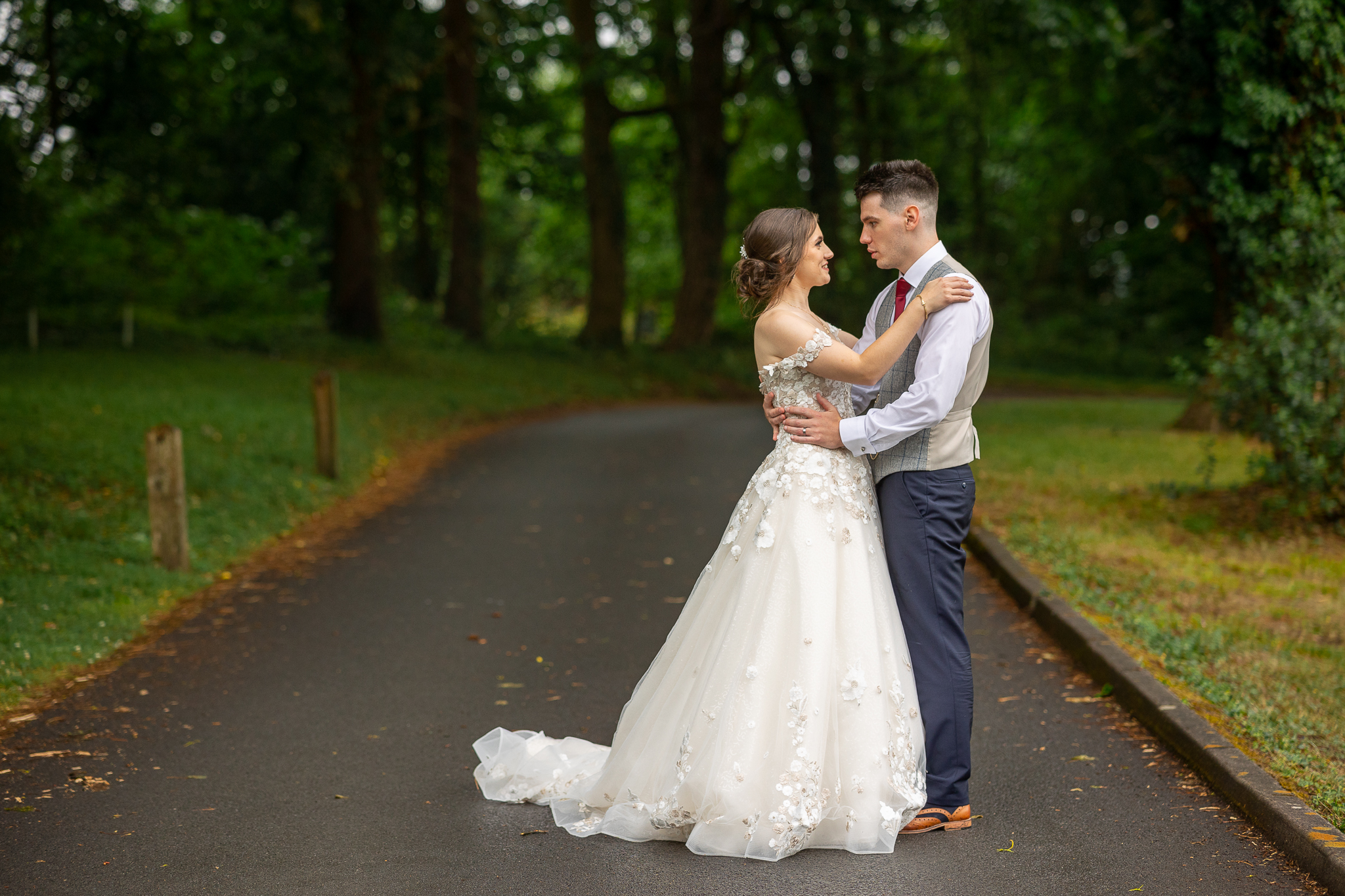 A bride and groom embracing on a path in the woods, captured by a South Wales wedding photographer.