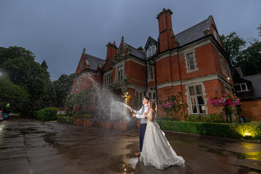 A bride and groom standing in front of a large mansion at night.