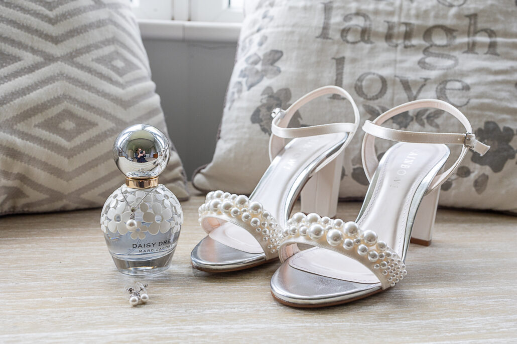 A pair of high heeled shoes and a perfume bottle on a table.