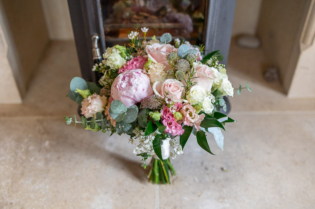 A bouquet of pink and white flowers sits in front of a fireplace.