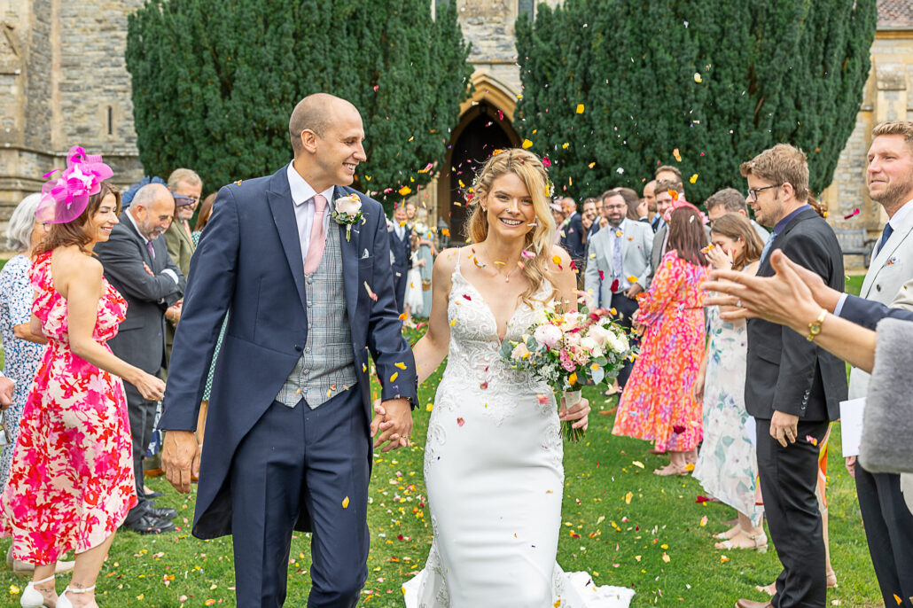 A bride and groom walk through confetti at their wedding.