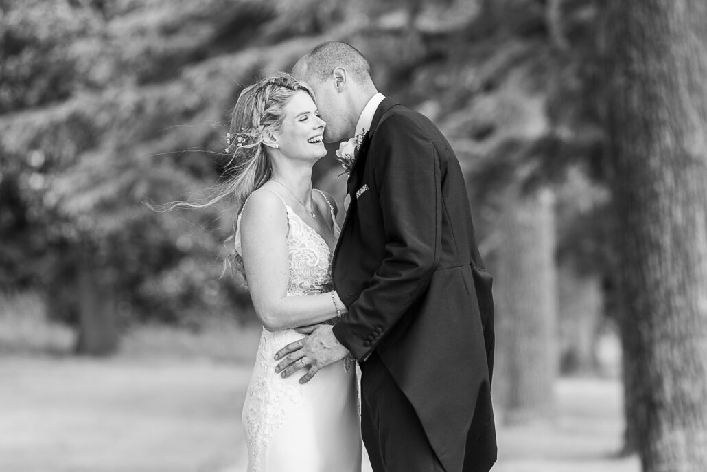 Black and white photograph of a bride and groom kissing.