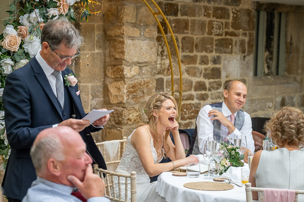 A bride and groom laughing at their wedding speech.