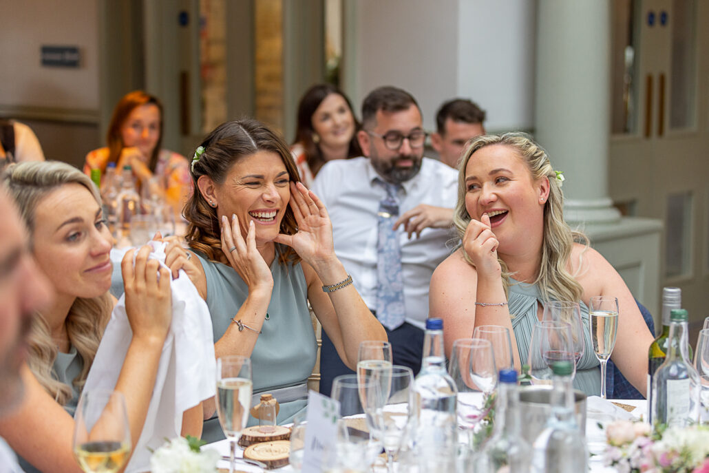 A group of bridesmaids laughing at a wedding reception.