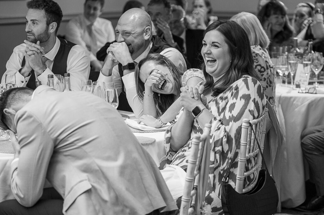 A black and white photo of people laughing at a wedding.