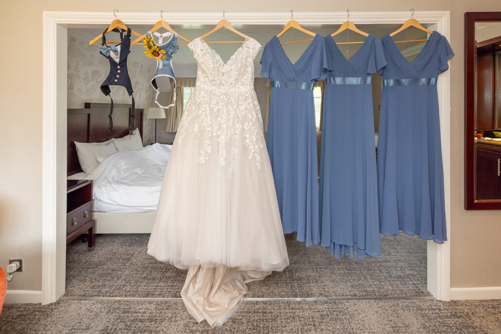 A bride's dress hangs on a hanger in a hotel room.