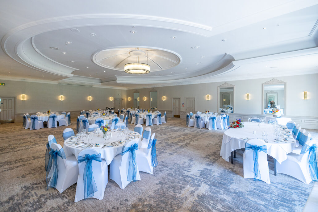 A wedding reception in a large room with blue and white tablecloths.