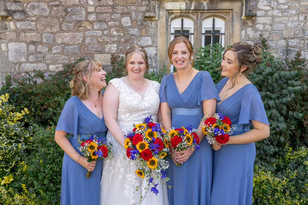 Four bridesmaids with bouquets in front of a castle.
