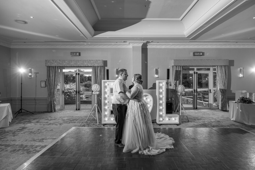 Black and white photo of bride and groom dancing in the ballroom.