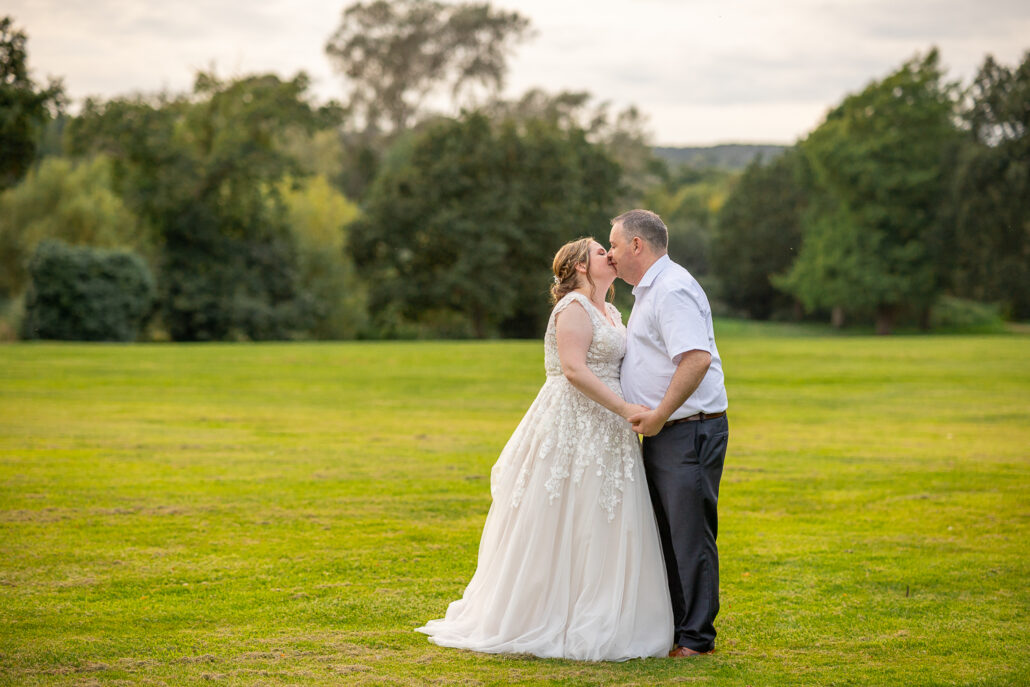 A bride and groom kissing in a field.