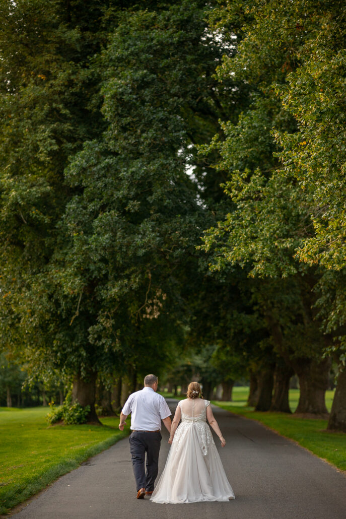 A bride and groom walking down a path.