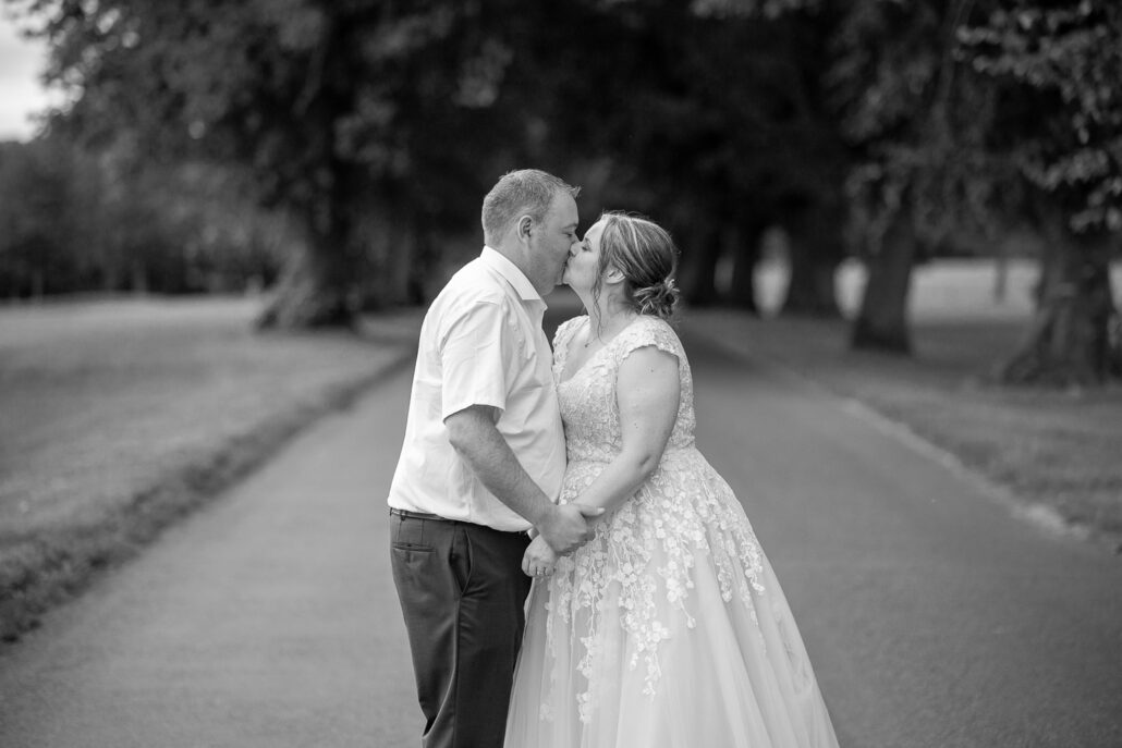 A bride and groom kissing on a road.