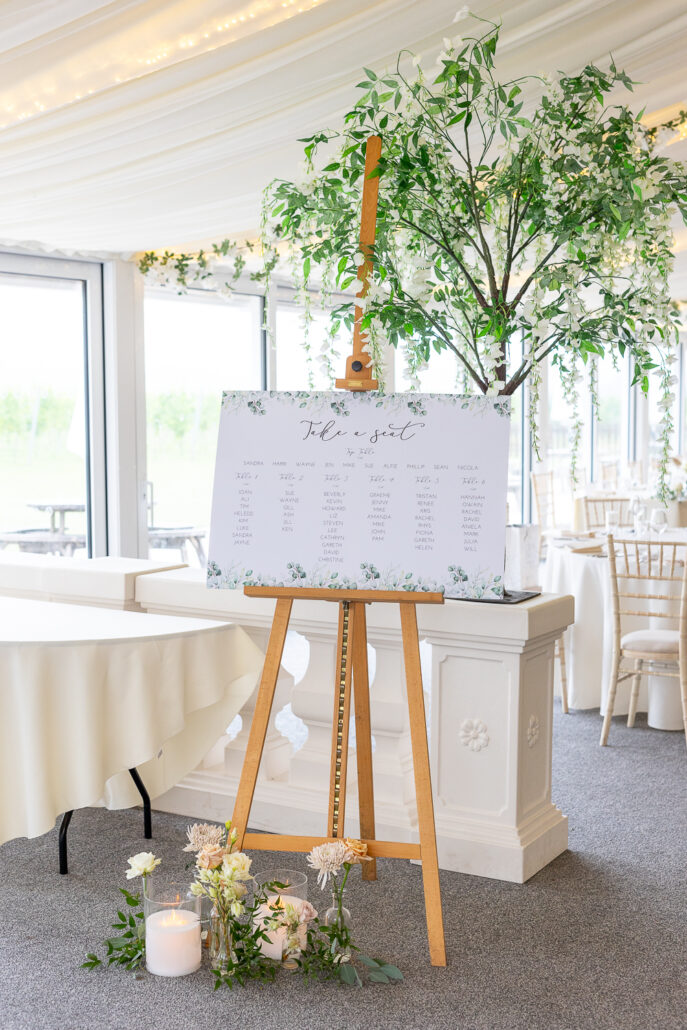 A table with a white easel and flowers.