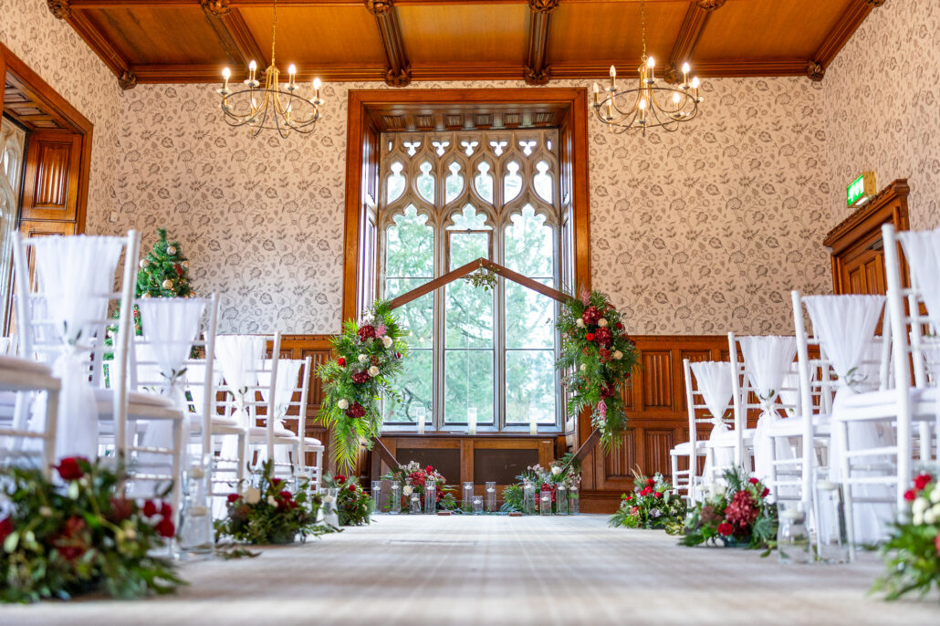 A wedding ceremony in a room with white chairs.