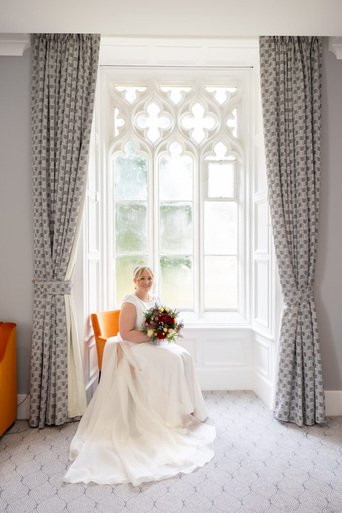 A bride sitting in front of a window in a room.