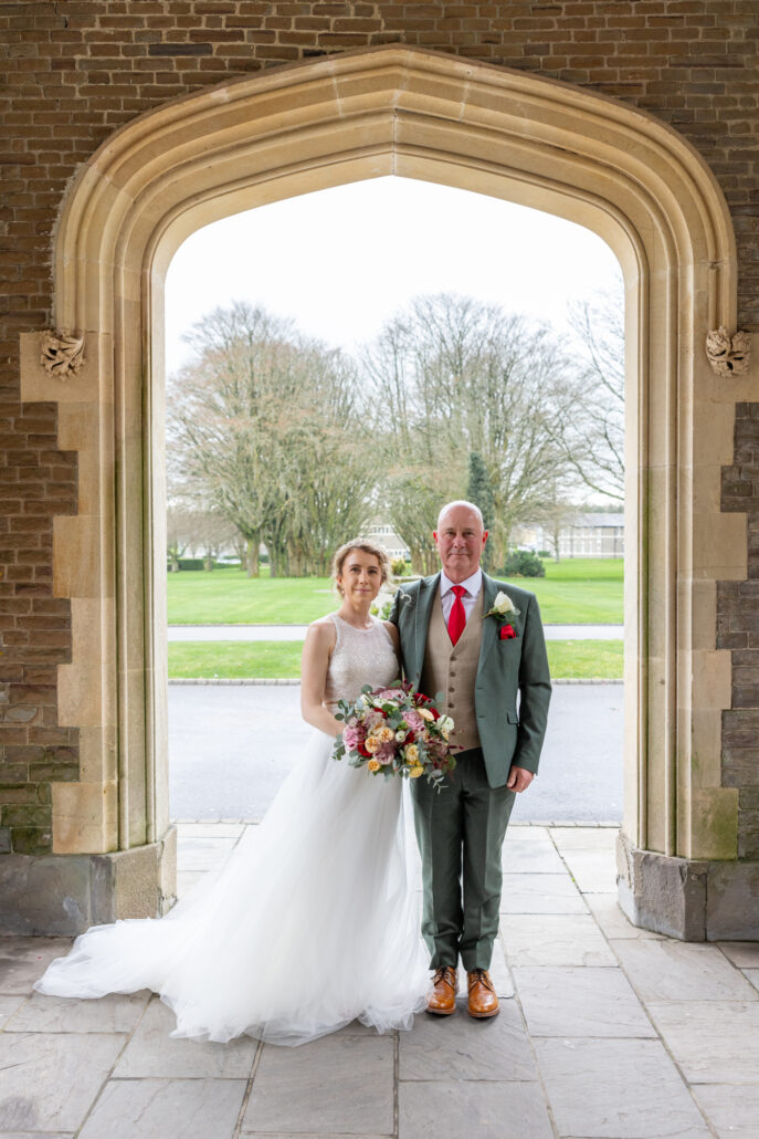A bride and groom standing in front of an archway.