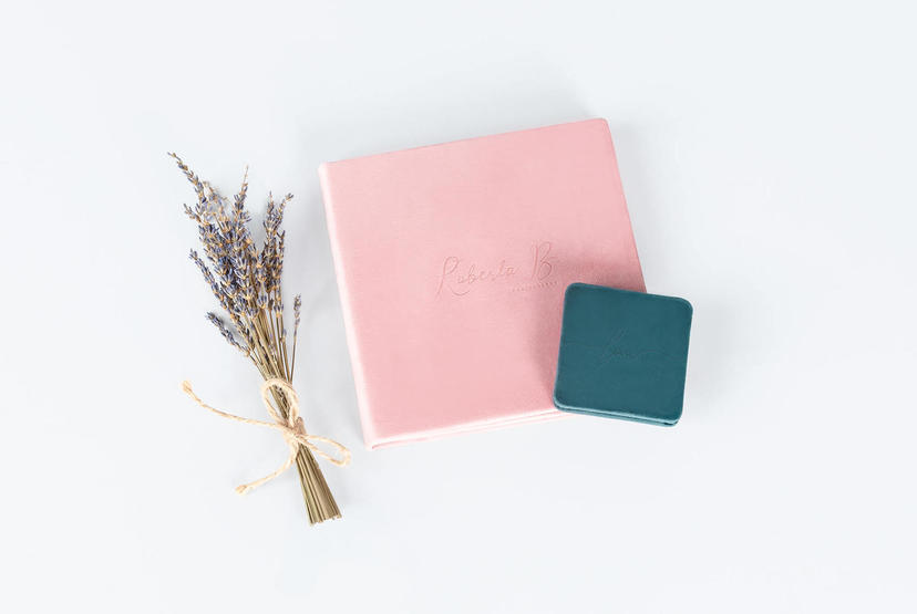 Pink notebook, teal square box, and tied bundle of dried lavender on a light surface.